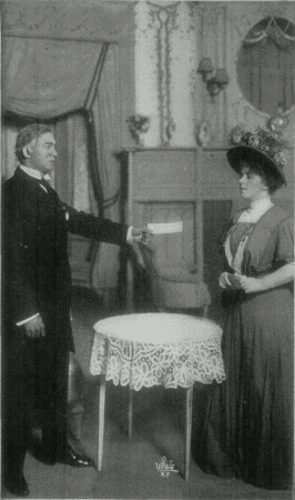 [Photo, from the play, of Mr. Ryder holding out a cheque to Shirley.]