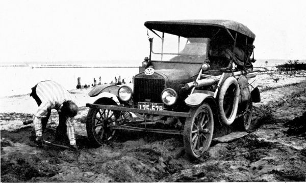 Man digging a car out of a rut.