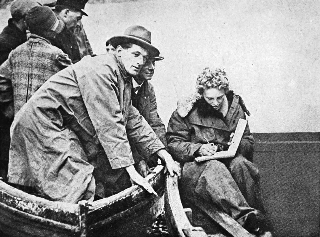 Photo full shot of sitting Earhart signing a book