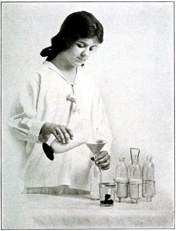 A woman using a funnel to fill bottles