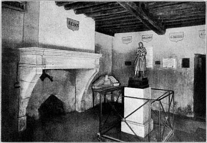 Kamer in het huis waar Jeanne d'Arc te Domremy woonde.
   Het huis wordt zooveel mogelijk in den oorspronkelijken toestand bewaard. In het midden een standbeeld van Jeanne.--Naar een photographie.